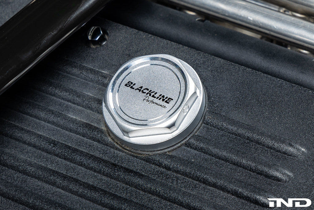 Goldenwrench BMW M Blackline Heritage Motorsport oil cap installed on car engine exterior, showcasing sleek black design.