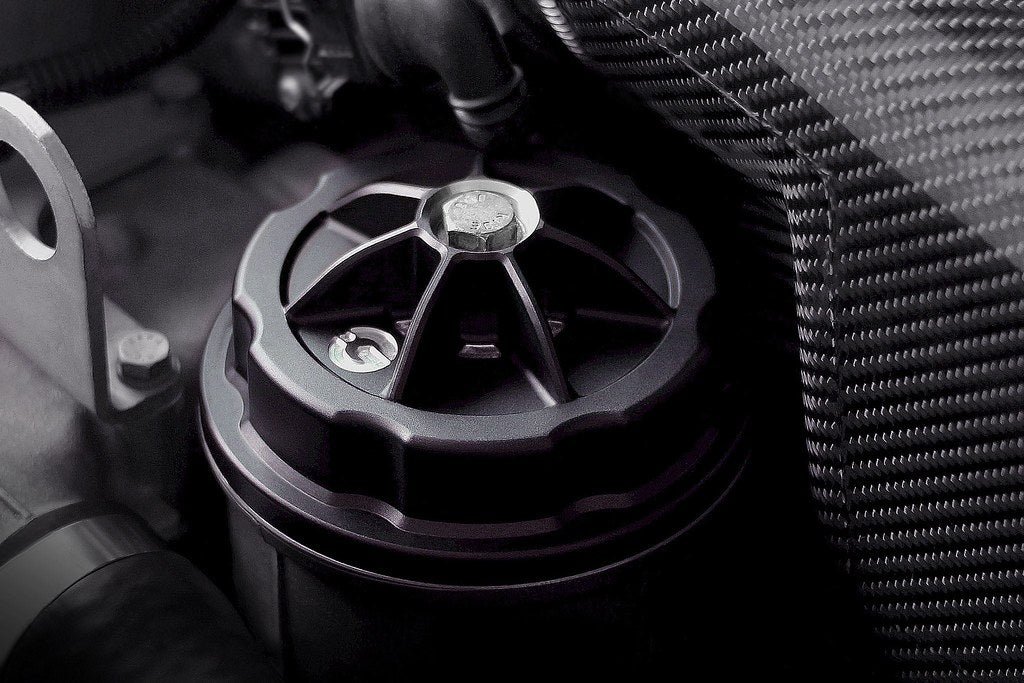 Goldenwrench BMW M50 S50 S52 S54 oil filter cap installed, exterior view showing black metal cap on engine.