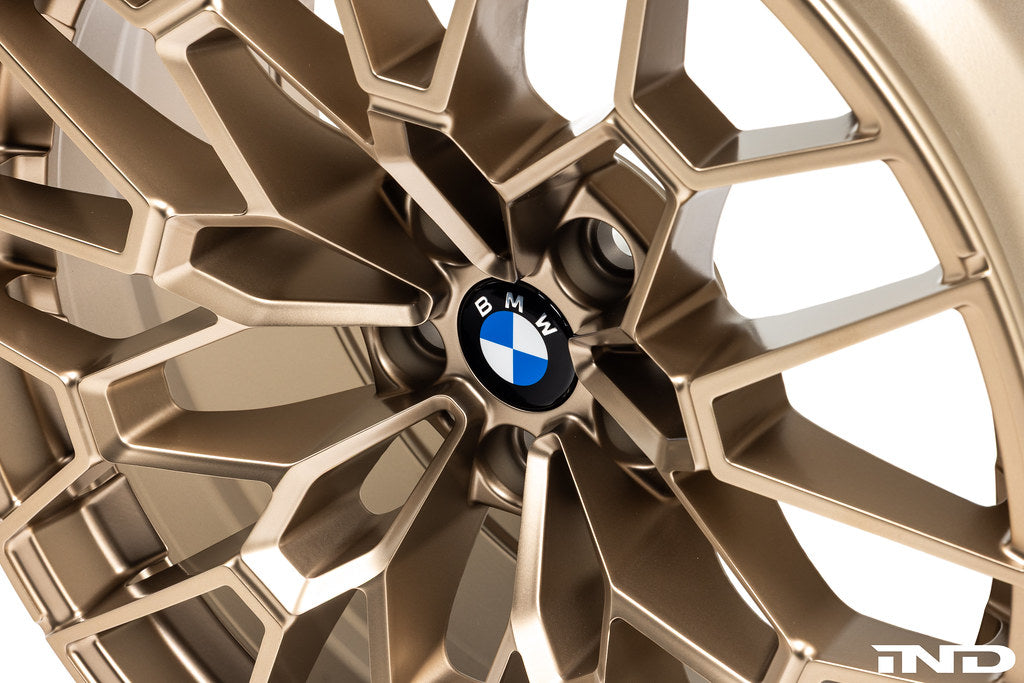 IND Gloss Black BMW wheel center cap set, 56mm Next Dark design installed on gold wheels, with a white background.