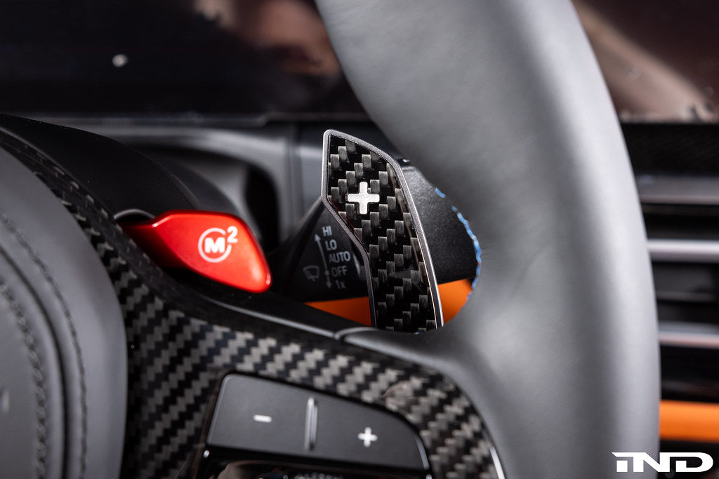 JQ Werks MadTrace BMW G-Chassis Clubsport magnetic carbon fiber shift paddles installed on steering wheel interior.