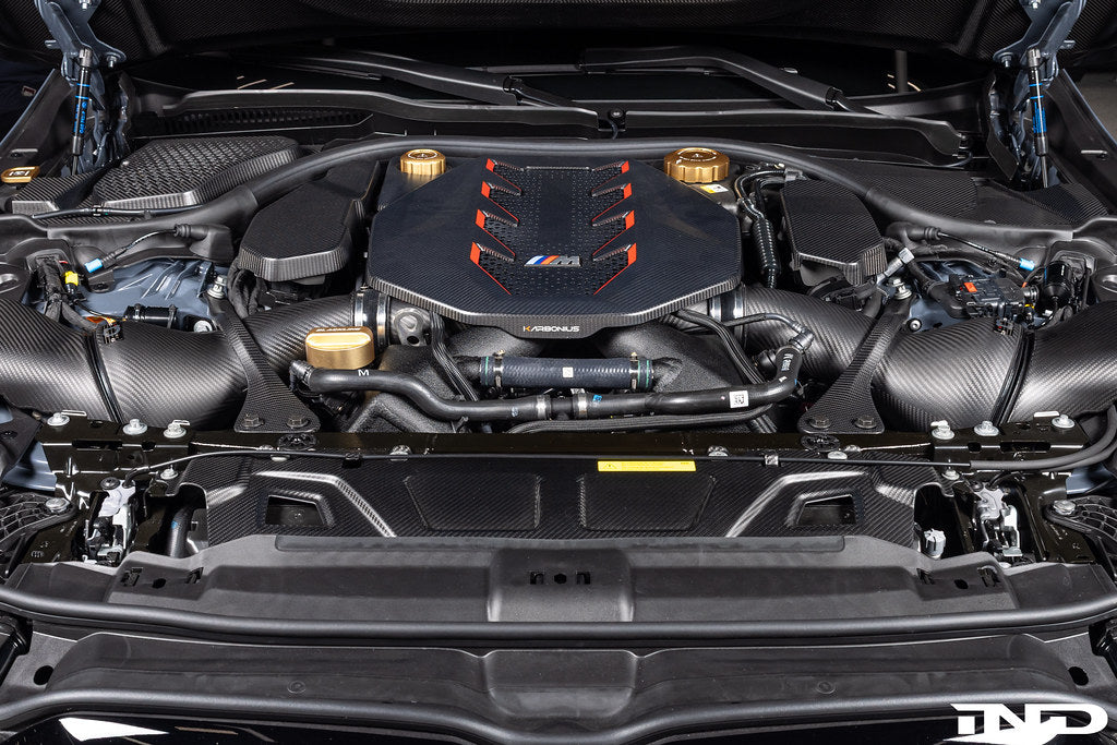 Karbonius G90 G99 M5 carbon fiber suspension strut brace set installed in a vehicle for improved chassis rigidity.