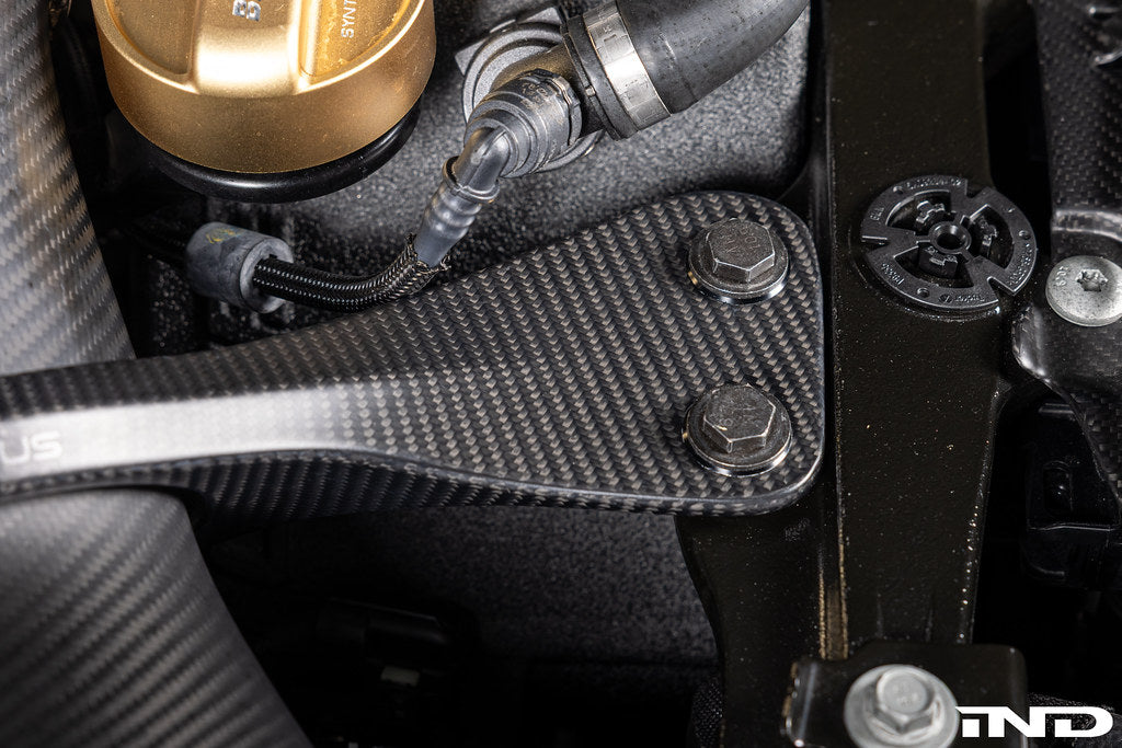 Karbonius G90/G99 M5 carbon fiber suspension strut brace set installed in a vehicle engine bay.