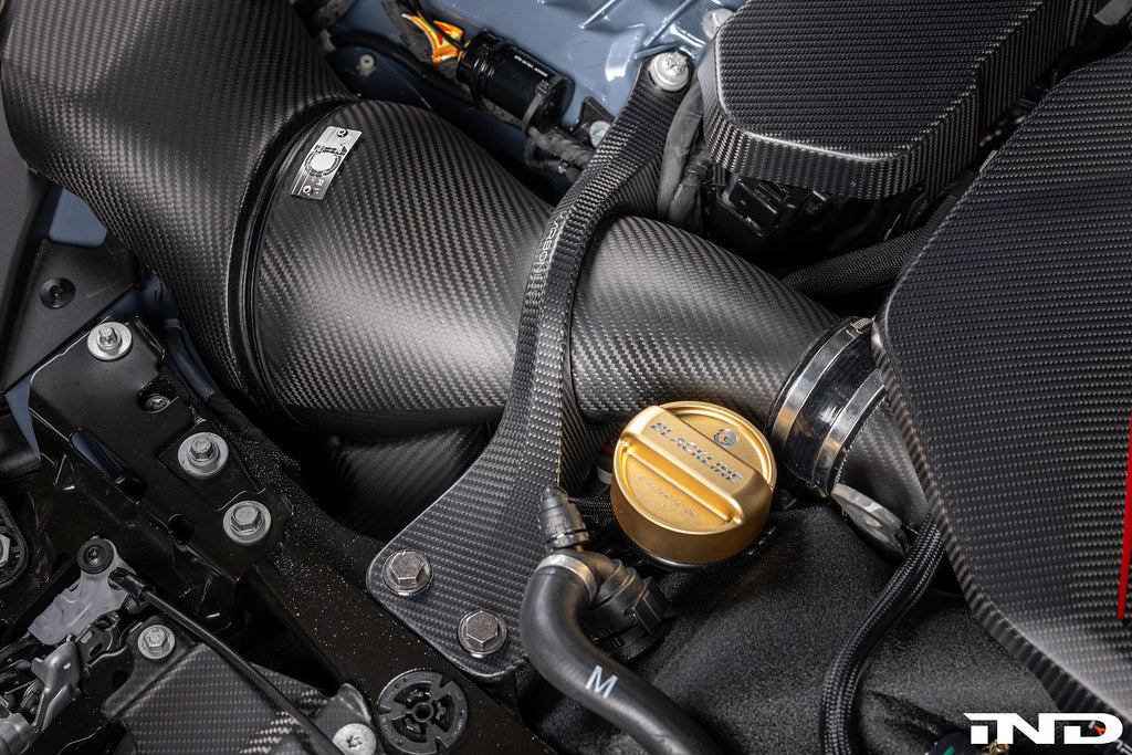 Karbonius G90 G99 M5 carbon fiber suspension strut brace set installed on a vehicle's engine bay.