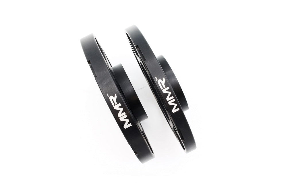 Black anodized MMX Performance BMW and Supra 5x112 wheel spacer kit with 12mm, 15mm, and 18mm spacers shown on wheels.
