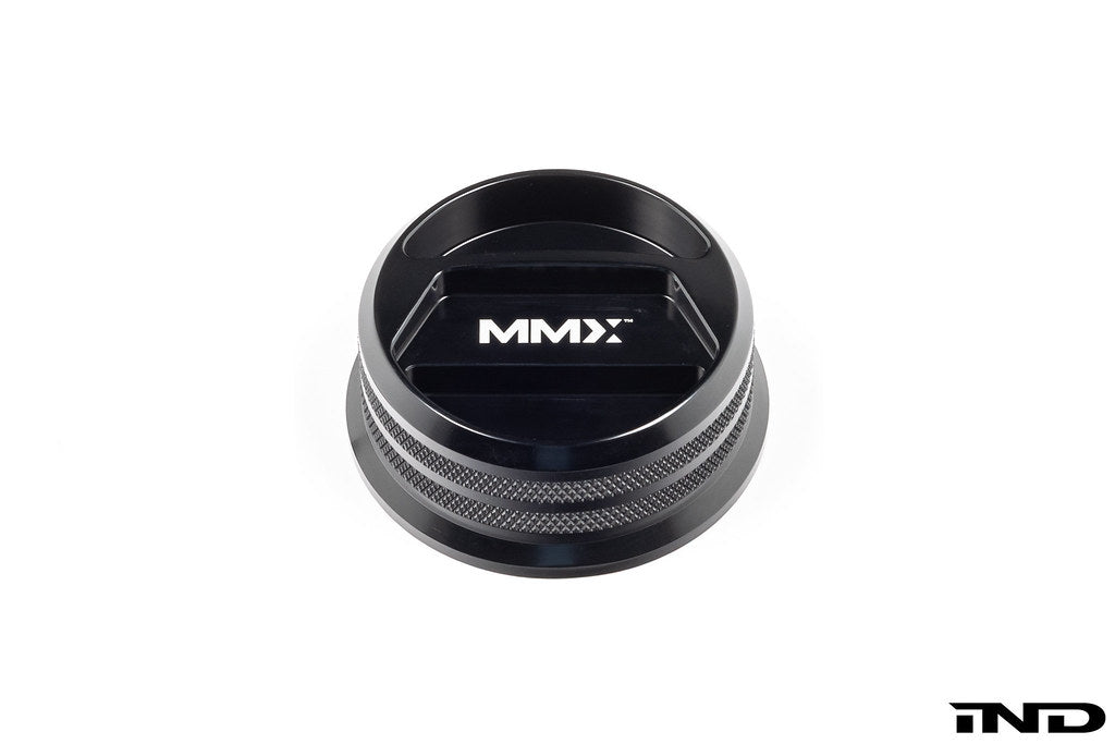 Black anodized MMX Performance BMW billet oil filler cap with engraved branding, designed for high-performance vehicle engine maintenance.
