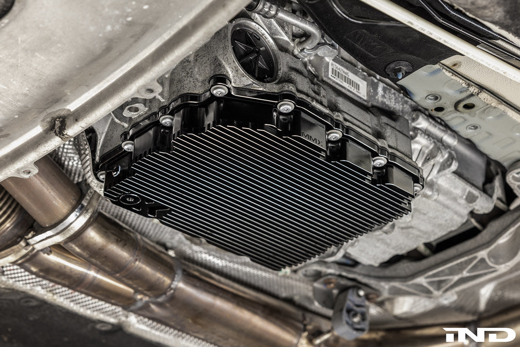 Black anodized MMX Performance aluminum BMW DCT oil pan installed on vehicle, designed for high-performance transmission cooling.