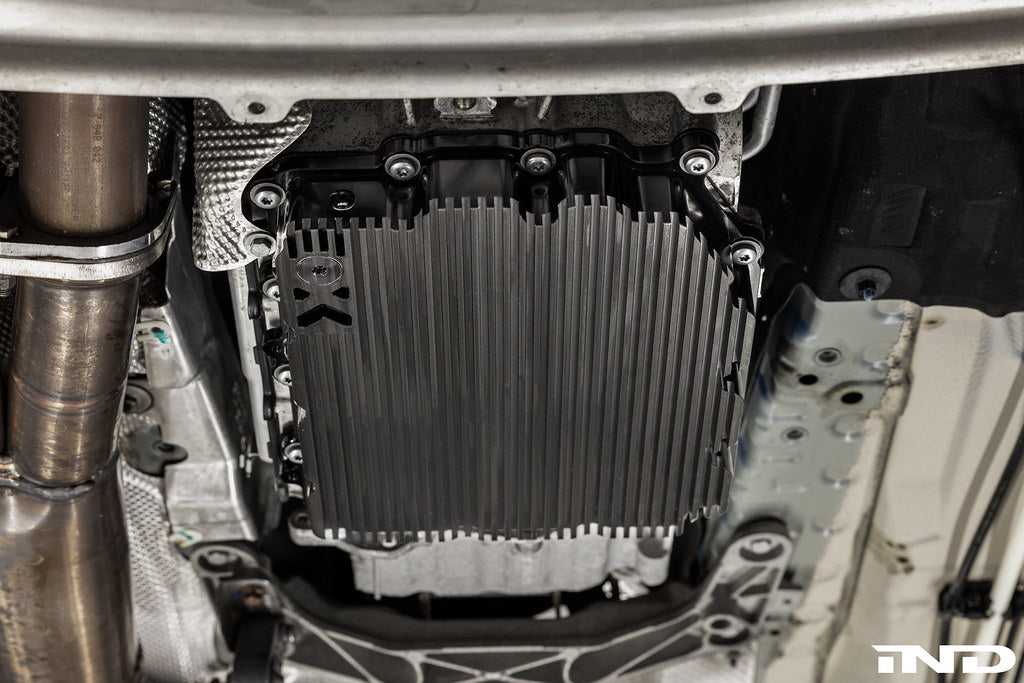 Black anodized MMX Performance aluminum BMW DCT oil pan installed on vehicle, showcasing durable and lightweight design for enhanced performance.