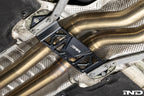 MMX Performance Underbody Chassis Brace installed on a BMW F8X M2, M2 Competition, M3, or M4, providing an additional 15mm of exhaust clearance while maintaining factory ground clearance and increasing chassis rigidity.