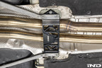 MMX Performance Underbody Chassis Brace installed on a BMW F8X M2, M2 Competition, M3, or M4, providing an additional 15mm of exhaust clearance while maintaining factory ground clearance and increasing chassis rigidity.