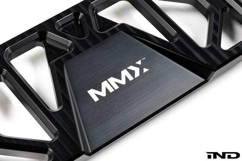 MMX Performance BMW F8X Underbody Chassis Brace on a white background, precision CNC machined from billet 6061-T6 aluminum to increase exhaust clearance, improve chassis rigidity, and provide a direct OEM-fit installation for the F87 M2, M2 Competition, F80 M3, and F82/F83 M4.