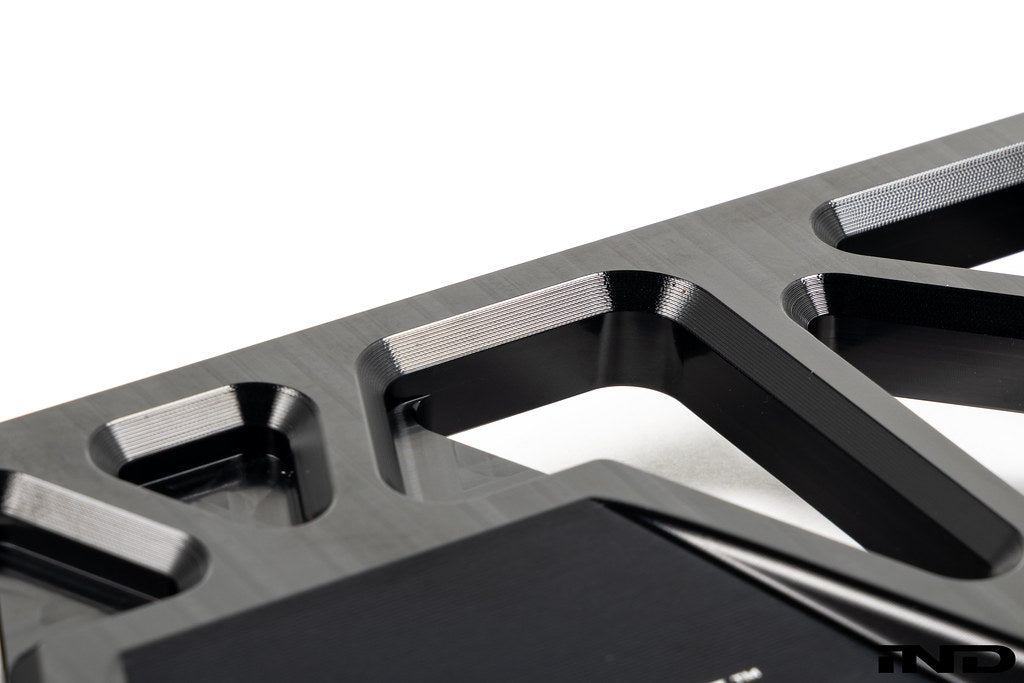 MMX Performance BMW F8X Underbody Chassis Brace on a white background, precision CNC machined from billet 6061-T6 aluminum to increase exhaust clearance, improve chassis rigidity, and provide a direct OEM-fit installation for the F87 M2, M2 Competition, F80 M3, and F82/F83 M4.