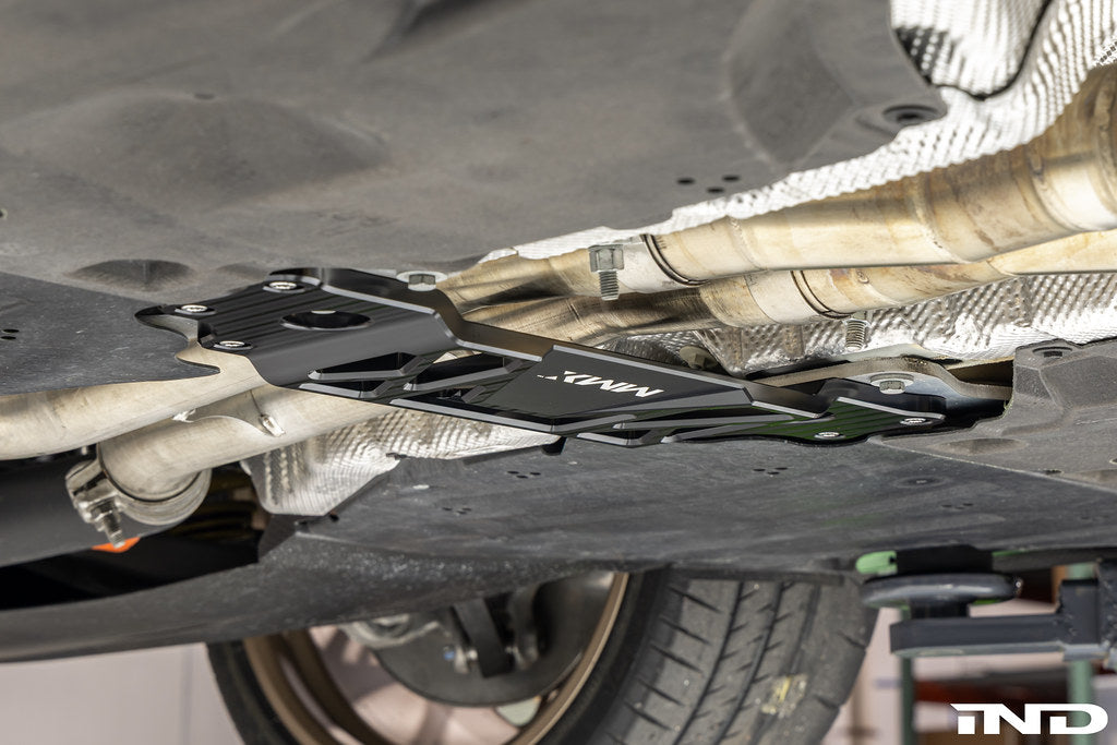 MMX Performance BMW G87 M2 Underbody Chassis Brace installed, providing an additional 15mm of exhaust clearance while maintaining factory ground clearance and increasing chassis rigidity with a precision billet 6061-T6 aluminum design.