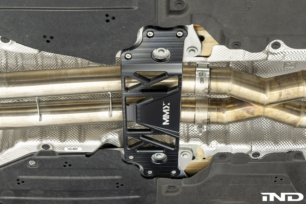 MMX Performance BMW G87 M2 Underbody Chassis Brace installed, providing an additional 15mm of exhaust clearance while maintaining factory ground clearance and increasing chassis rigidity with a precision billet 6061-T6 aluminum design.