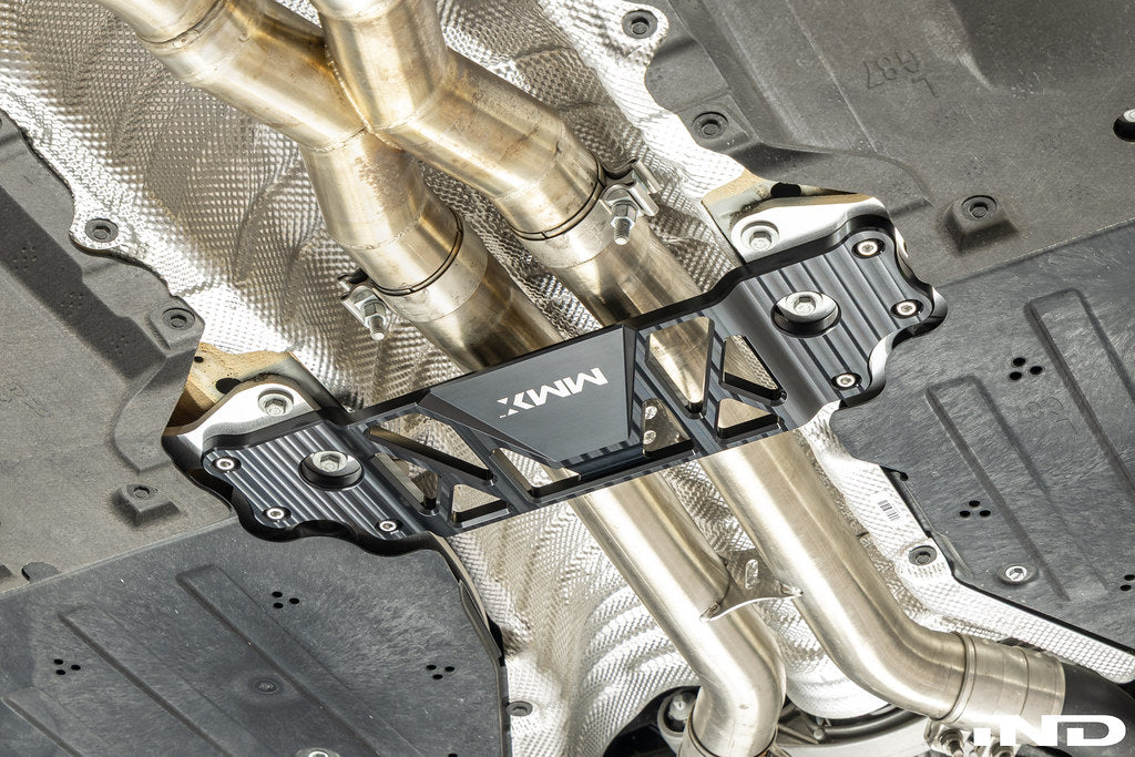 MMX Performance BMW G87 M2 Underbody Chassis Brace installed, providing an additional 15mm of exhaust clearance while maintaining factory ground clearance and increasing chassis rigidity with a precision billet 6061-T6 aluminum design.