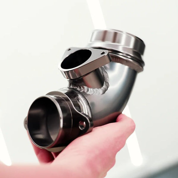 MMX Performance S58 turbo inlet elbow held in a person's hand, showcasing the CNC-machined 6062-T6 aluminum construction, integrated velocity stack, and high-quality welds for BMW G8X M2, M3, and M4 models.