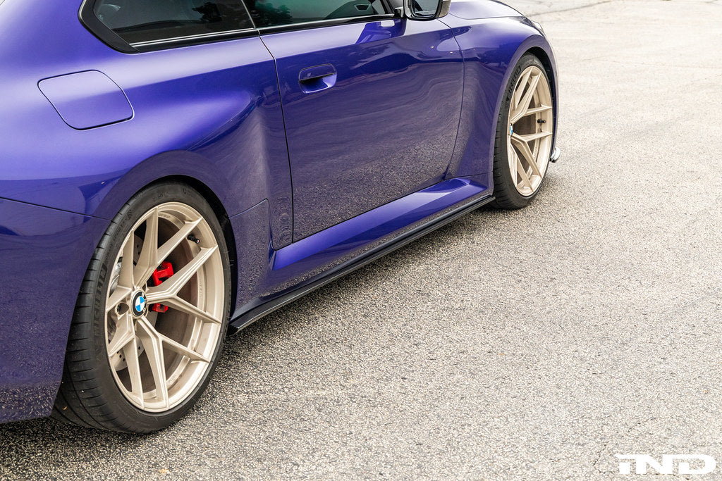 TREVORA carbon flat side skirts installed on a BMW G87 M2