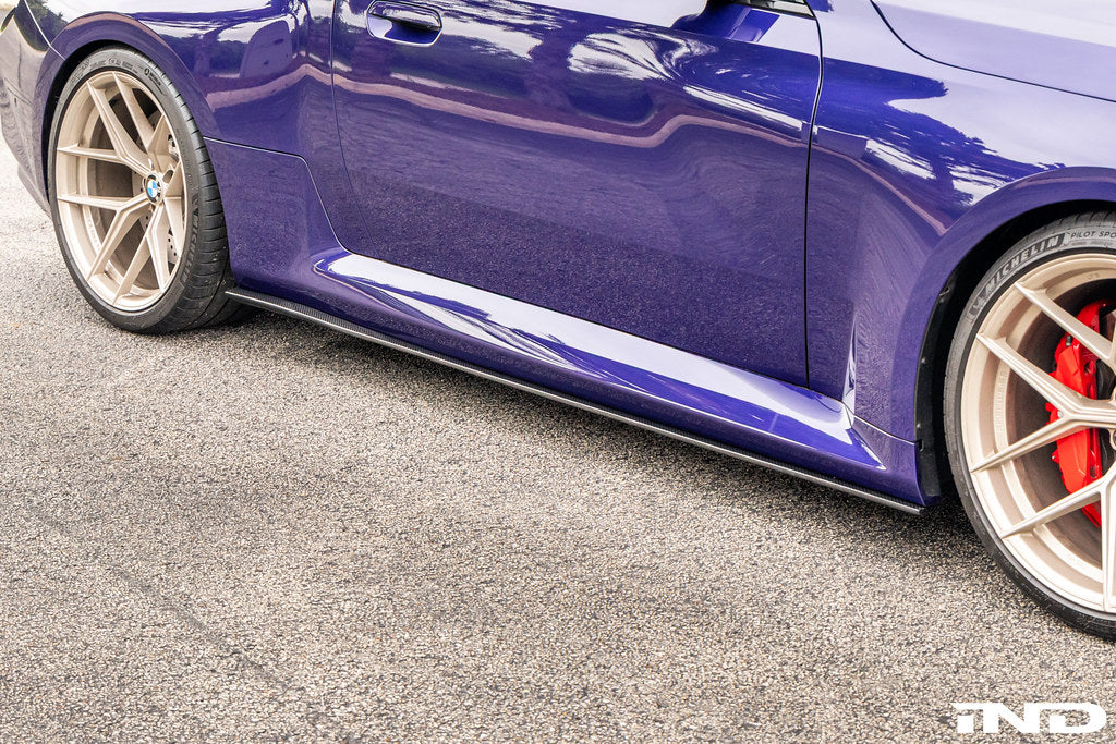 TREVORA carbon flat side skirts installed on a BMW G87 M2