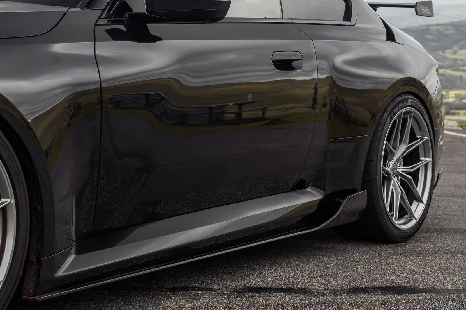 TREVORA G87 M2 Carbon side skirt set installed on a car, showcasing sleek exterior design and aerodynamic features.