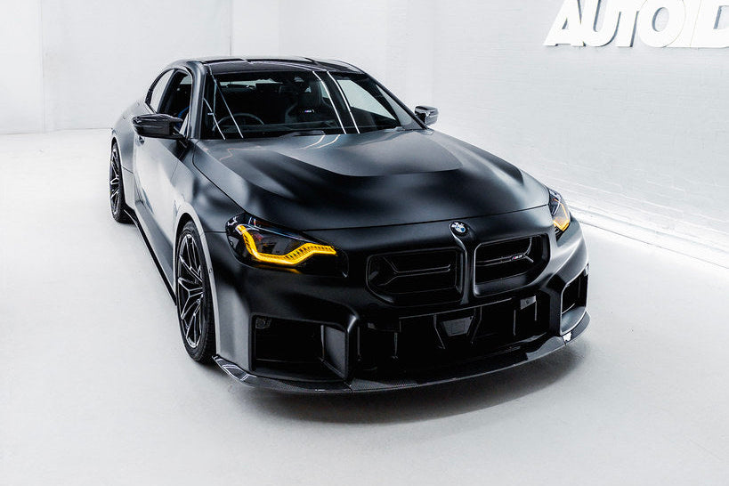 TREVORA BMW G87 M2 TR87 Ultimate Carbon Kit exterior with flat front splitter installed on black car, showcasing sleek design.