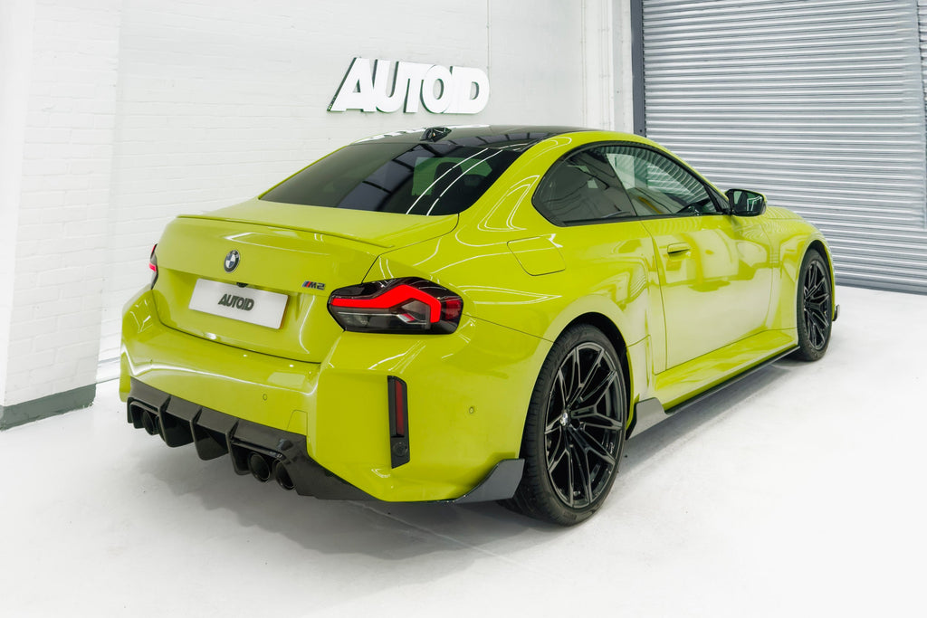 TREVORA G87 M2 Carbon rear bumper winglet set installed on exterior of BMW M2, showcasing sleek aerodynamic design.