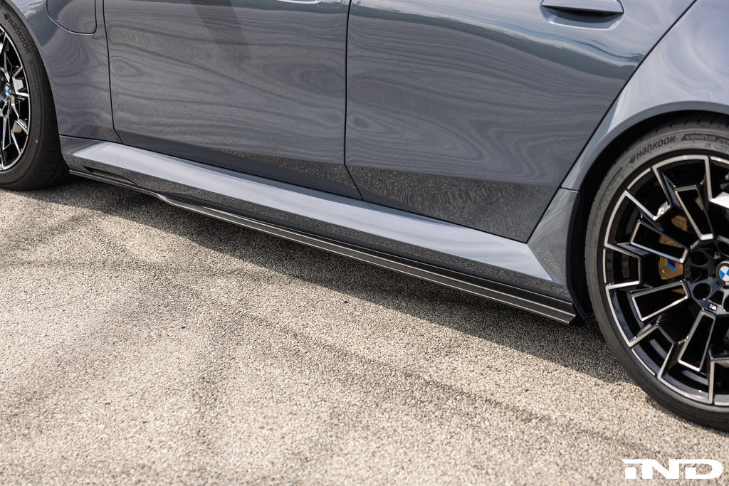 TREVORA BMW G90 G99 M5 PR-1 carbon exterior side skirts installed on the vehicle.