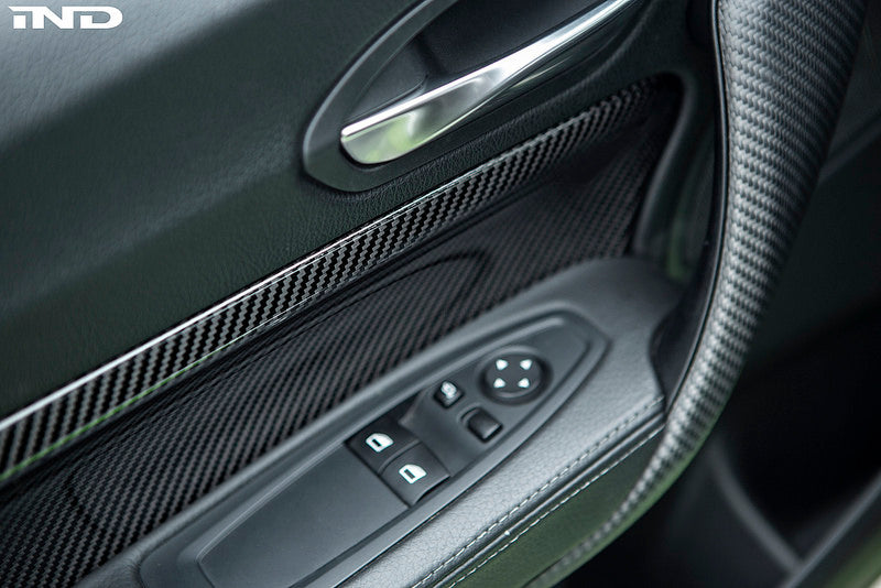 Alpha N F87 M2 carbon interior door card set installed, showcasing sleek, lightweight carbon fiber accents on vehicle doors.