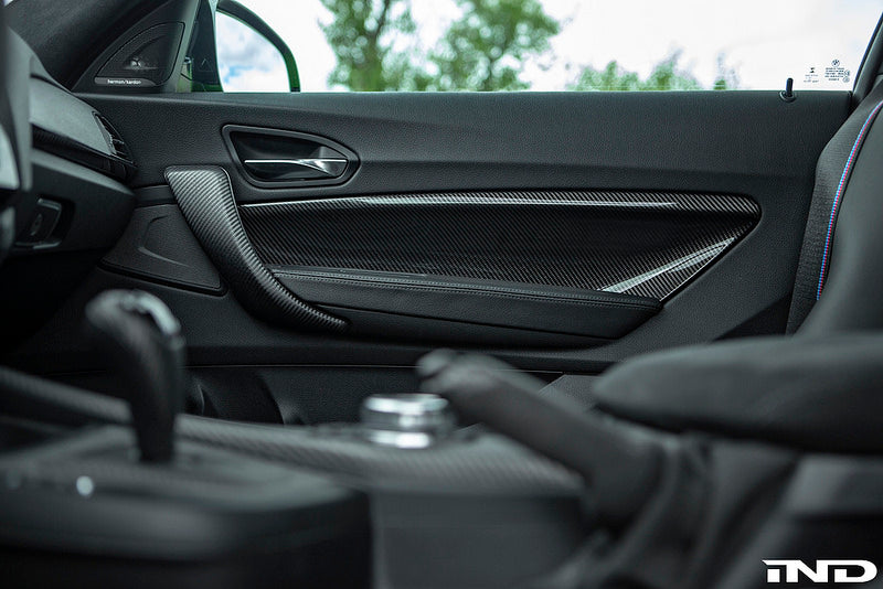 Interior view of Alpha N F87 M2 Carbon Door Card Set installed, showcasing sleek carbon fiber accents on car door panels.