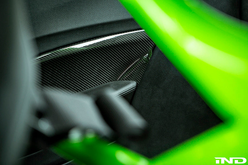 Alpha N F87 M2 carbon interior door card set installed in a vehicle, showcasing sleek black carbon fiber finish and detailed craftsmanship.