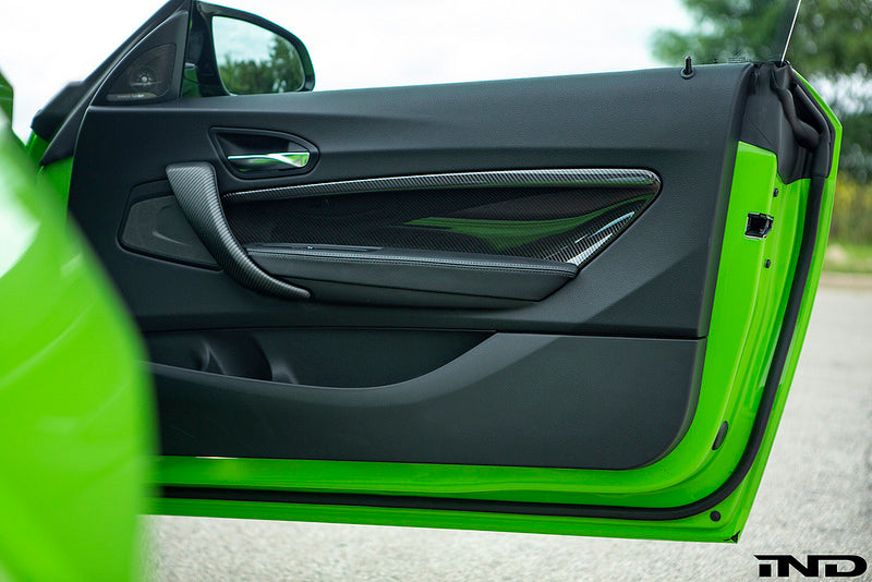 Alpha N F87 M2 carbon door card set installed in car interior, showcasing sleek carbon fiber finish and detailed design elements.
