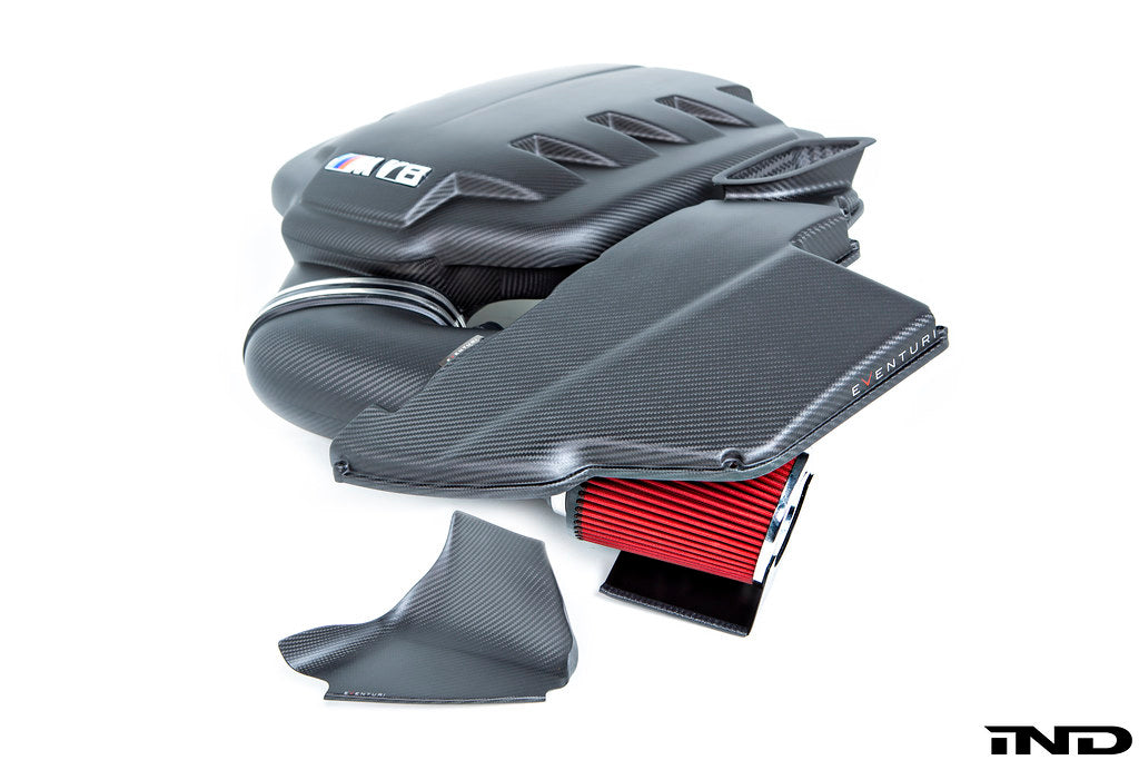 Front quarter view of the Eventuri black carbon fiber inlet plenum for BMW E9X M3 assembled with the carbon intake system all in matte finish on a white background