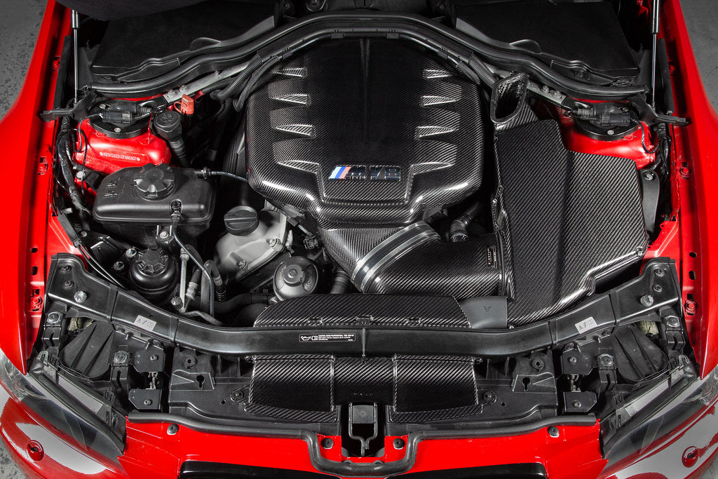 Eventuri gloss carbon fiber duct set installed in the engine bay of a red BMW E92 M3 Coupe