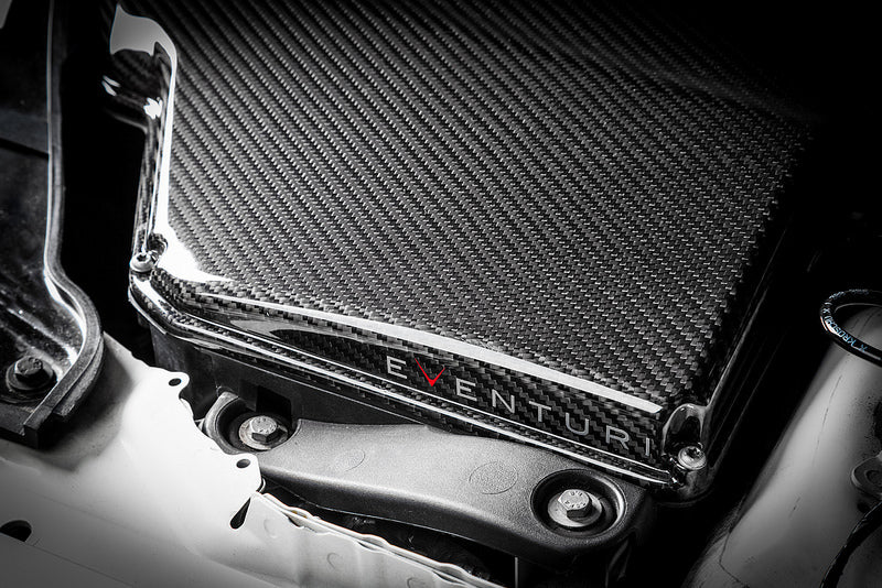 Eventuri black carbon airbox lid installed on BMW E9X M3 S65 engine for improved performance and sleek gloss finish.