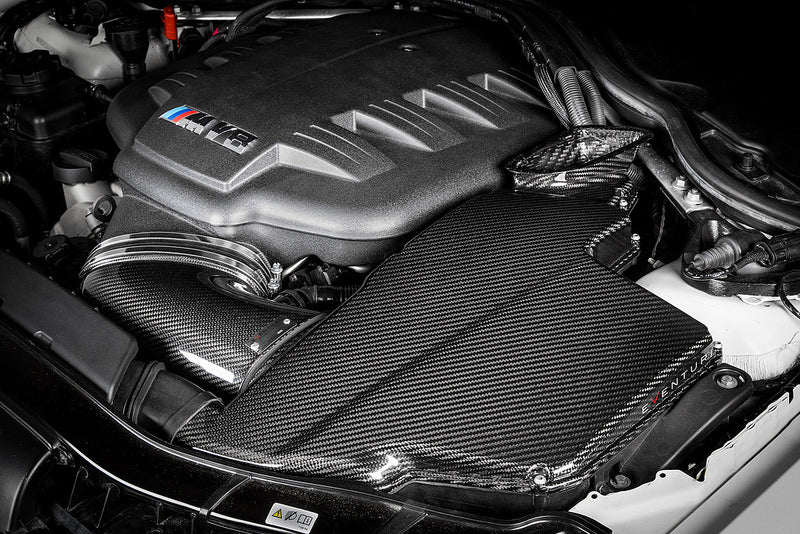 Eventuri black carbon airbox lid installed on BMW E9X M3 S65 engine for enhanced performance and sleek gloss finish.