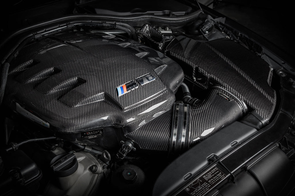 Eventuri black carbon inlet plenum installed in BMW E9X M3 (S65) engine bay, showcasing gloss finish and high-performance design.