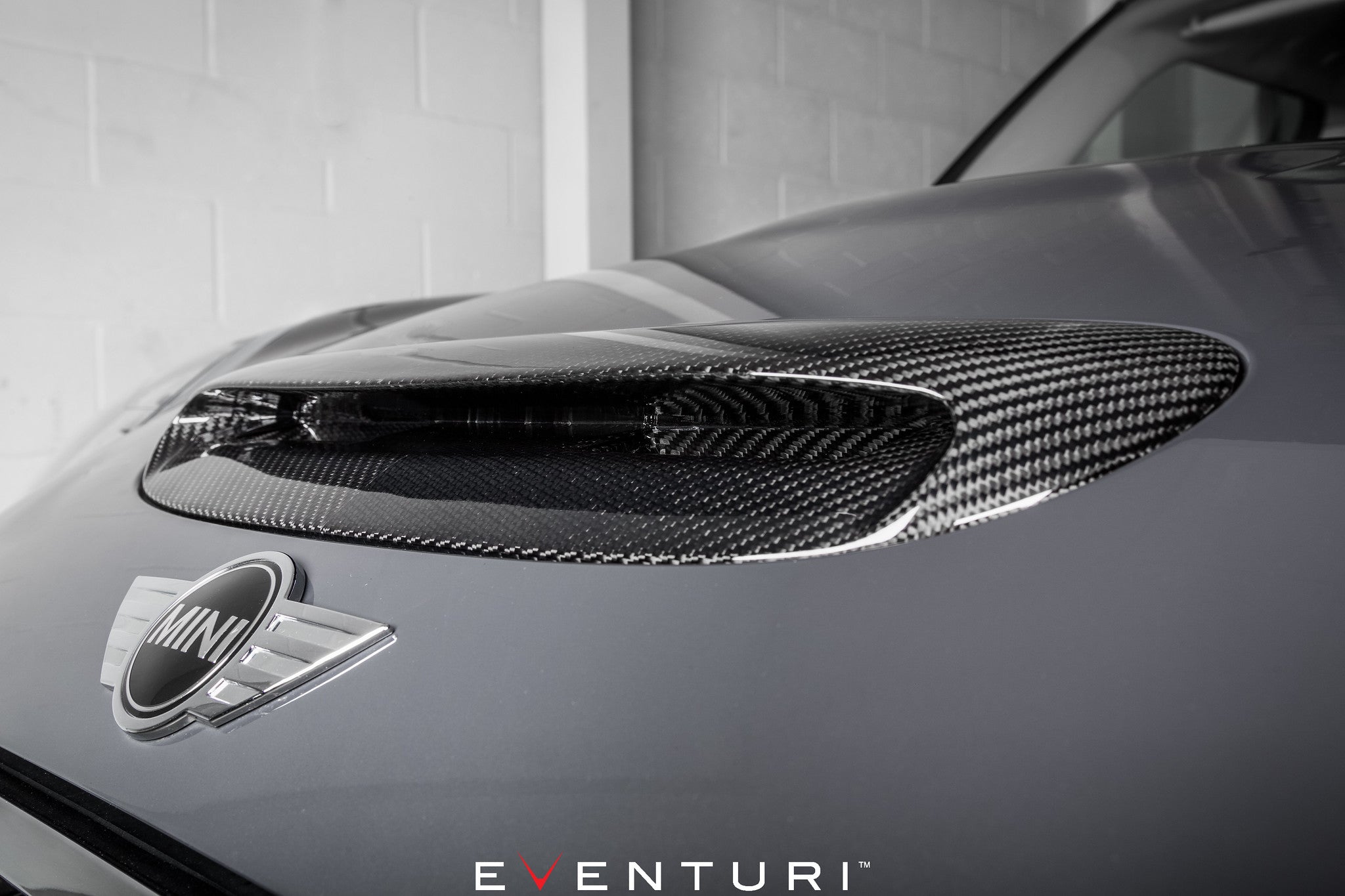 Eventuri F56 Mini Cooper S plastic intake with carbon scoop, exterior view showing glossy carbon hood scoop for enhanced performance.