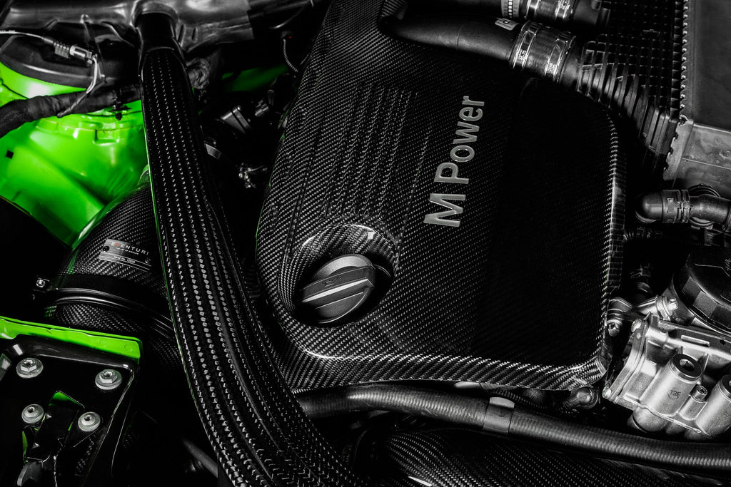 Eventuri black carbon intake system installed in engine bay of BMW F8X M3 and M4 with S55 engine, showcasing performance upgrade.